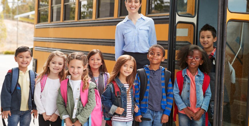 Elementary,School,Teacher,And,Pupils,Standing,By,School,Bus
